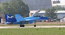 Side view of blue jet aircraft taxiing right with canopy open