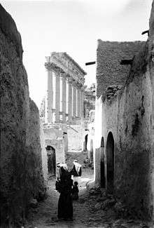 People in an alley, with ruins in the background