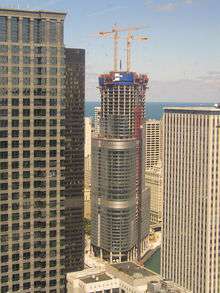  a tall skyscraper under construction in the middle of a city viewed from an elevation of about 40 stories in another building