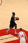 A basketball player in a dark blue uniform has the ball in his hands in the open court.