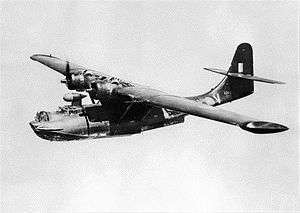 Black-painted twin-engined military amphibious aircraft in flight