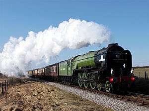 Steam locomotive in green livery hauling a passenger train