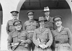 Six officers pose for a formal group portrait. Two are wearing slouch hats, the remainder are wearing peaked caps. All have multiple ribbons.