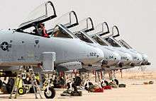 Side view of five jet aircraft with canopies opened parked side-by side.