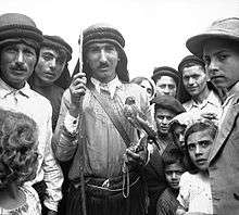 Man holding a falcon, in the centre of a group of people