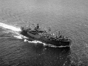 Aerial view of cargo ship at sea, with numerous large cranes and other loading equipment visible on the decks fore and aft