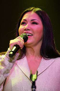 Ana Gabriel, behind a microphone pedestal.