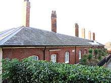 A terrace of red brick single story dwellings.