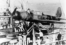 Black-and-white photo of a seaplane surrounded by people