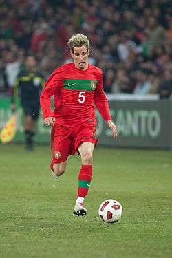 A man with red shirt and red shorts running with a football