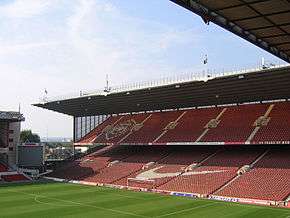 A grandstand at a sports stadium. The seats are predominantly red.