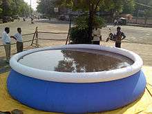 Large blue above-ground pool, with four men standing around it