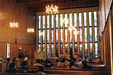 Inside a church, facing the altar and the stained glass church windows.