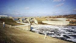  A small river rushes away from the base of a dam.