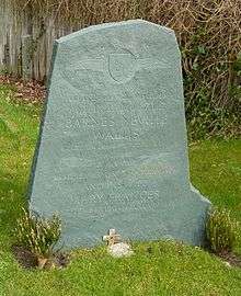 Irregular green gravestone standing in a grassy churchyard