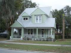 a green two story house with shingles