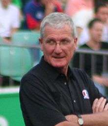 A head and shoulder shoot of an Englishman standing at the Taunton Cricket Ground, wearing a black shirt and spectacles