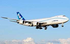 Quarter view of quadjet on approach over clouds.