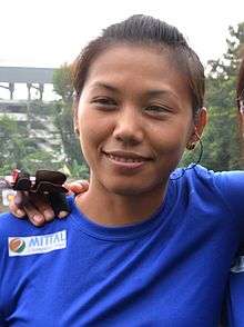 Laishram smiling at the camera in a blue jersey.