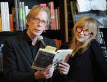 Legs McNeil holds a book with Gillian McCain standing next to him