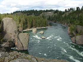 A stream of water in front curving around some large boulders