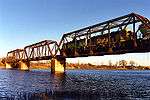 A train crosses a bridge over a wide river.