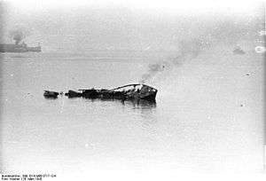 small ship smoke rising and sinking. In the background is a pier