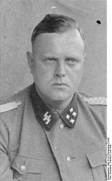 A man in semi profile wearing a military uniform. His hair is combed back and his facial expression is determined.