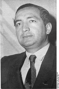 Black-and-white portrait of a man in semi profile wearing a suit and tie.