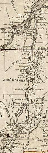 The map is oriented with north to the top. The lower section of the map shows Saratoga, New York and Fort Edward, on the Hudson River. There are red markers depicting the position of John Burgoyne's army near Saratoga at the time of its surrender in 1777. A line of mountains is shown to the right of the Hudson, extending northward but eventually bending off the map to the east. North of Fort Edward are Fort George, at the southern end of Lake George, and Skenesborough, near the southern end of Lake Champlain. About one third of the way up the map, Lake George joins with Champlain, and Fort Ticonderoga is shown at the northwest side of the junction, with Fort Crown Point a little further north. Lake Champlain extends to the north and is dotted with islands. There is a red line marking the boundary between New York and Quebec, and the upper third of the map shows the Richelieu River extending north to meet the Saint Lawrence River at Sorel, with Montreal southwest of that point. Fort Saint John and Fort Chambly are to the left of the Richelieu, about halfway between the boundary line and Montreal.