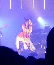 A woman singing on a blue stage.