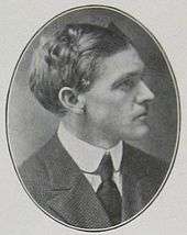 Head and shoulders of a man of about 35 in profile in an oval frame. He is wearing a dark suit and tie and a white collar. His hair is dark, full, and wavy.