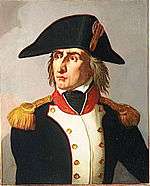 Color print of an angry looking man with a long nose and long hair. He wears a large bicorne hat and a dark blue military coat with white lapels, gold epaulettes and a red collar.