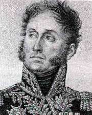 Black and white print of a man with mutton chops, round eyes and wavy hair. He wears a high-collared military uniform with much braid.