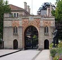 A grey and red stone and archway at the end of a road. A central arch for vehicles is flanked each side by smaller pedestrian arches