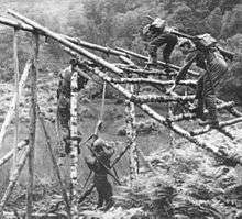 Man climbing over assault course wooden obstacle