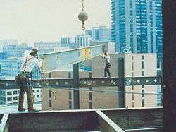 Two construction workers positioning a beam