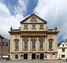 An imposing eighteenth-century building with three entrance archways, large first-floor windows and an ornate peaked gable end above.