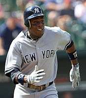 A baseball player running. He is wearing a gray jersey and a dark blue batting helmet; the jersey has a blue "NEW YORK" in the front, and the helmet has a white interlocking "N" and "Y" logo.