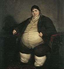 Smartly dressed fat man with dark hair sitting on a chair