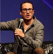 Aronofsky kneeling while holding a microphone