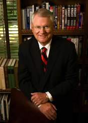 Man in suit in front of bookshelf