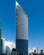 Ground-level view of a thin high-rises's curved, glass facade