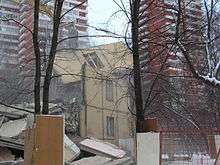 The remains of a low rise building are seen between two high rises