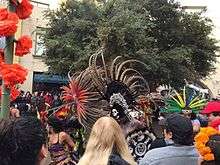 A parade with several dancers in elaborate headdresses