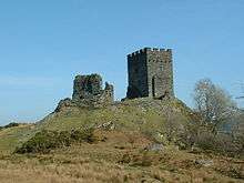 upon a grassy hillock stand two rectangular built fortifications. The one to the left is ruinous whilst the one to the right appears whole with battlements