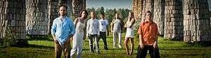  Photo of band members standing on a grass lawn between columns.