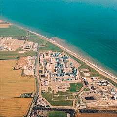 Aerial view of the gridiron arrangement of buildings and pipes beside the curving Yorkshire sea coast.