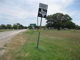 Photo shows a Farm to Market Road 2503 sign with a large oak tree as a backdrop. Photo was taken near the intersection with State Highway 71. View is northeast.