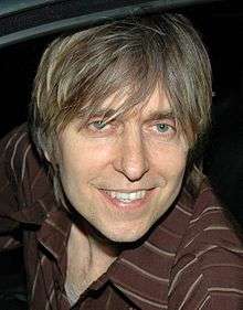 Head shot of a man wearing a brown-striped shirt